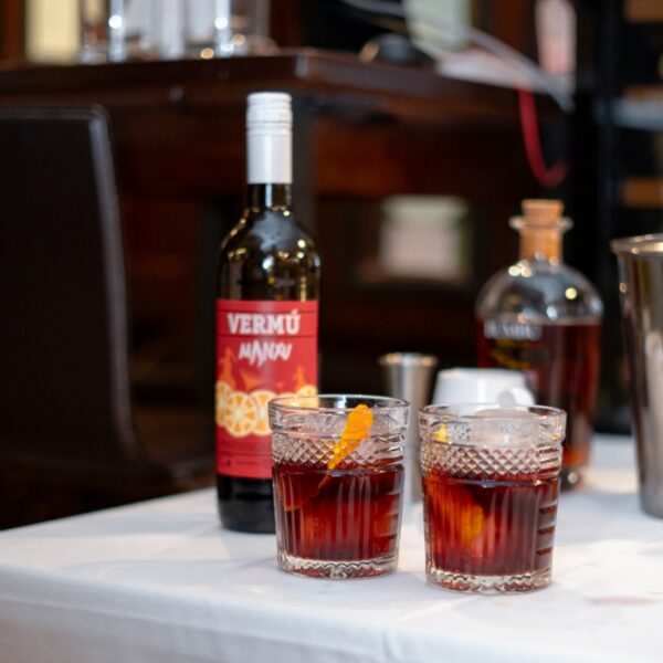 Botella y vasos de vermú en mesa.